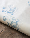 Roll of oilcloth with blue floral pattern on a wooden surface