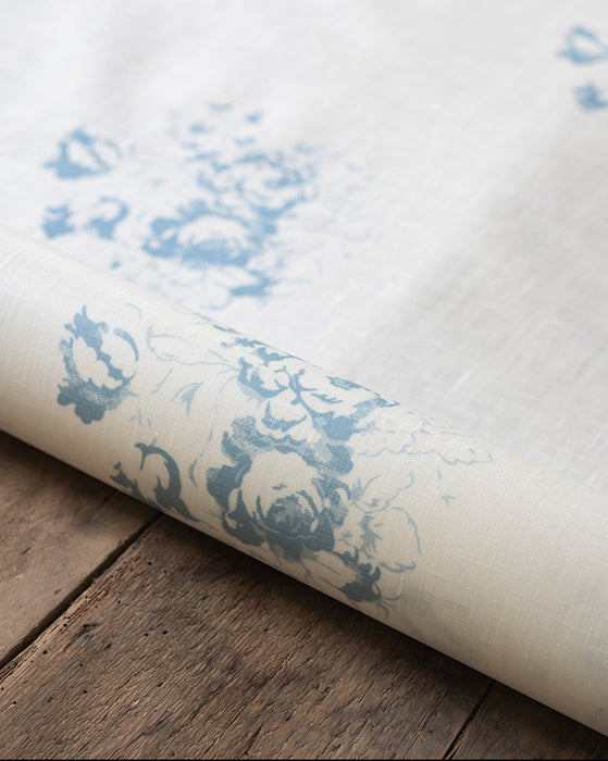 Roll of oilcloth with blue floral pattern on a wooden surface