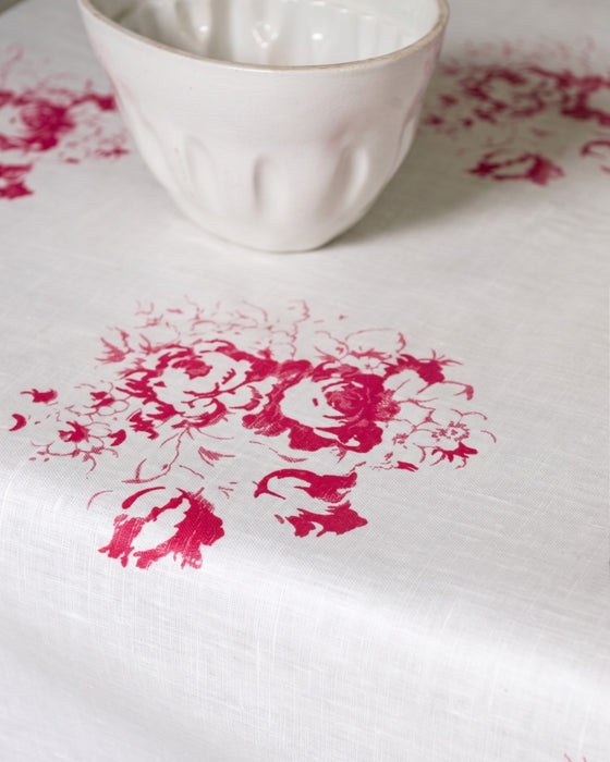 White ceramic cup on a white surface with pink floral patterns