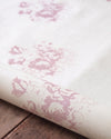 Roll of fabric with pink floral pattern on a wooden surface