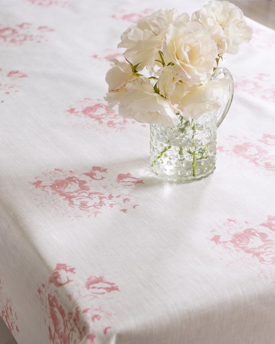 Clear glass vase with white flowers on a tablecloth with pink floral pattern